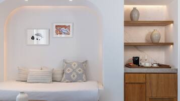 Une chambre moderne comprenant un lit, deux œuvres d’art encadrées et un coin cuisine avec un meuble en bois et une étagère.