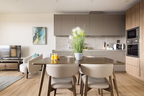 Una cocina moderna con comedor, armarios de madera, un televisor de pantalla plana y una planta en maceta.