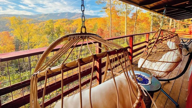 A hammock chair and a cushioned chair on a wooden deck with a view of autumn foliage. - Stunning Mtn View, True Log Cabin, Romance Getaway, Rare Find (Gatlinburg)
