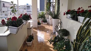 Ein Balkon mit Blumentöpfen und einem weißen Stuhl.