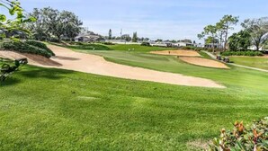 Een golfbaan met zandbunkers, verzorgd gras en een heldere lucht.