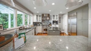 A modern kitchen with granite countertops, stainless steel appliances, and pendant lighting. - Juniper Presents: Magnificent Lakefront Vacay Home on the Beach (Coloma)