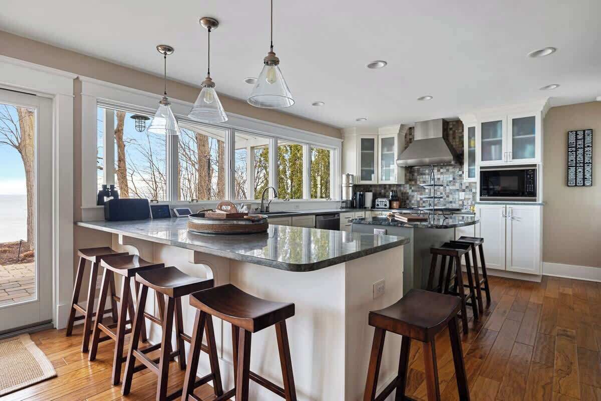 Una cocina moderna con una isla grande, taburetes de bar e iluminación colgante.