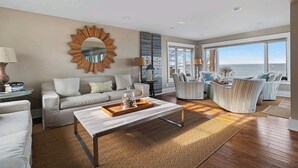 A modern living room with a sofa, armchairs, a coffee table, and a large mirror. - Juniper Presents: Magnificent Lakefront Vacay Home on the Beach (Coloma)