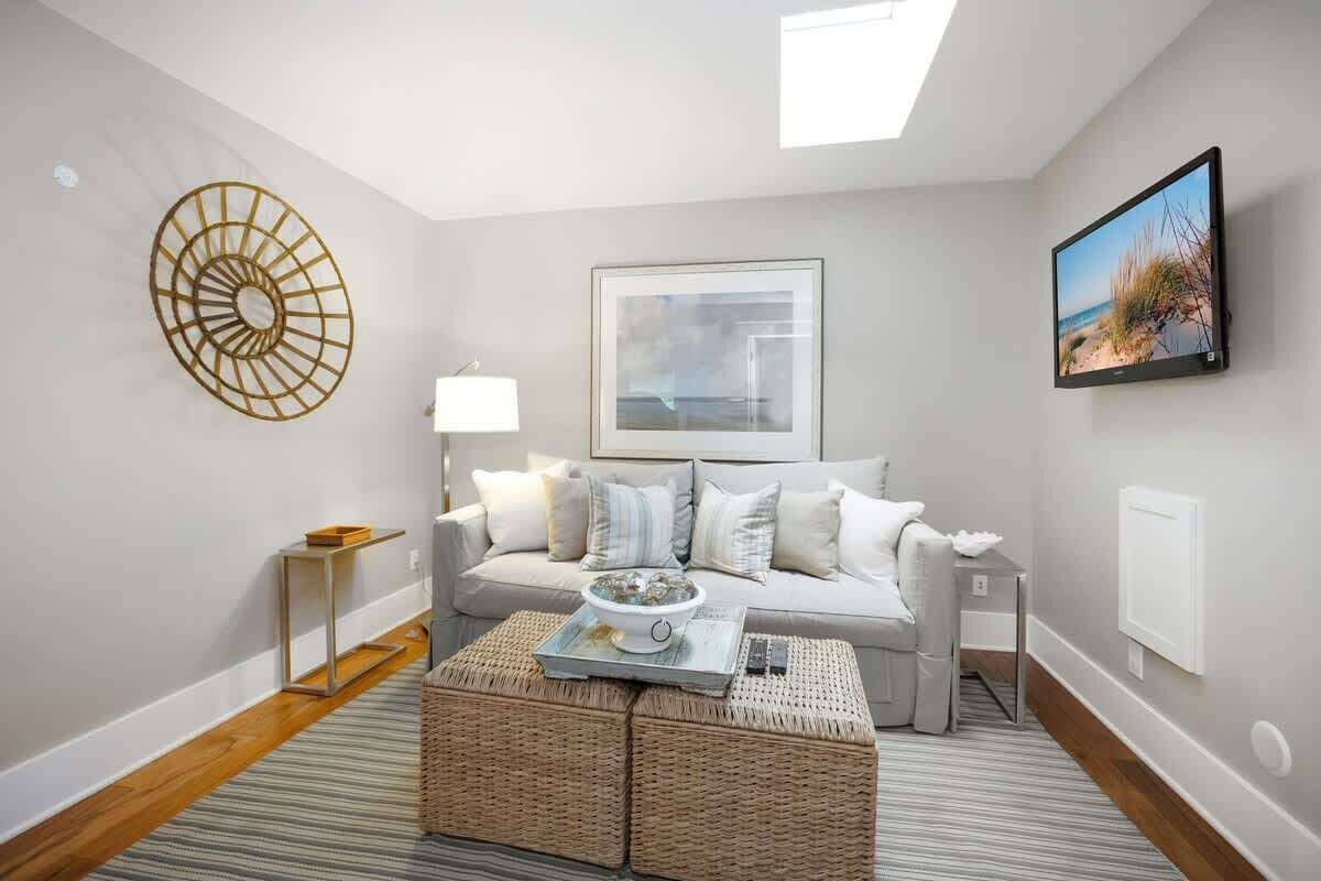A modern living room with a sofa, a coffee table, a wall-mounted TV, and a framed picture.