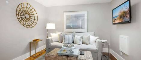 A modern living room with a sofa, a coffee table, a wall-mounted TV, and a framed picture.