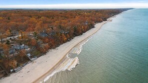 Een luchtbeeld van een strand met een rij huizen langs de kustlijn.
