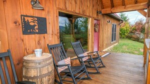 A wooden deck with rocking chairs and a barrel.