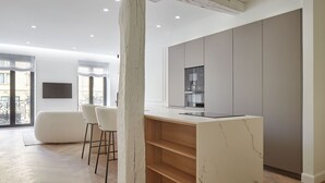 A modern kitchen with a marble countertop, built-in appliances, and a large window.