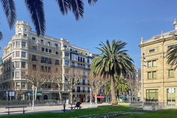 A public square with historic buildings, palm trees, and a café. - Opera | The Rentals Collection (San Sebastián)