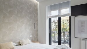 A modern bedroom with a large bed, a view of the outdoors through a balcony, and a radiator on the wall.