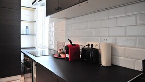 A modern kitchen with white subway tiles, a black countertop, and a window providing natural light. - Boho Apartments 2 Bedrooms (Antwerp)