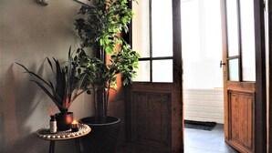 A room with a large potted plant, a small table with candles, and a wooden door. - Boho Apartments 2 Bedrooms (Antwerp)