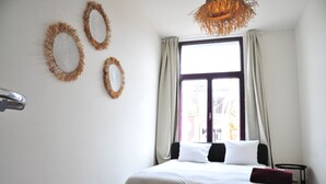 A bedroom with a bed, a window with curtains, and wall decorations. - Boho Apartments 2 Bedrooms (Antwerp)