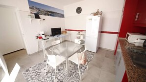 A compact kitchen with a dining table, chairs, a refrigerator, and a microwave. - The Story Guest House  (Faro)