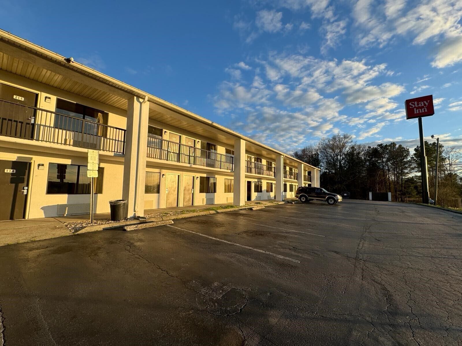 Un Stay Inn con un edificio de dos pisos, un estacionamiento y un cielo despejado.