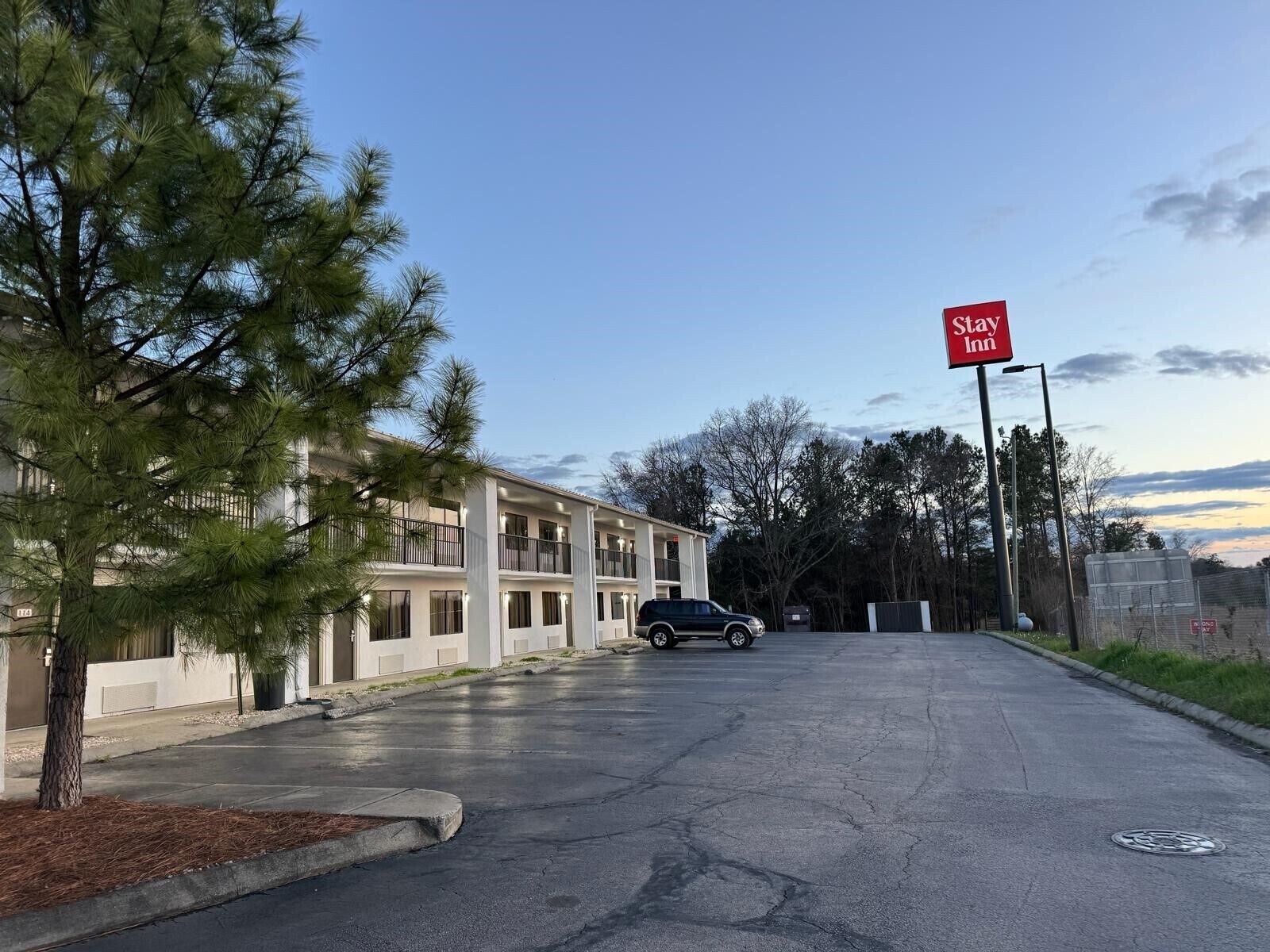 Un bâtiment de la chaîne Stay Inn avec un parking et une voiture garée devant.