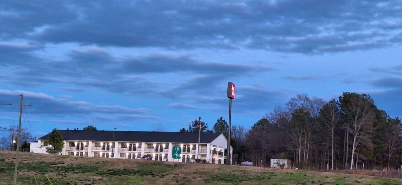 A large building with a prominent sign, surrounded by trees and a clear sky.