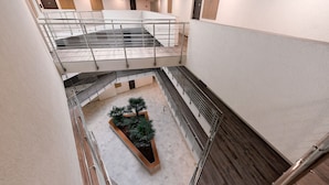 A multi-level interior with a central atrium, glass railings, and a potted plant. - Villa Oliver Hévíz 1 (Hévíz)