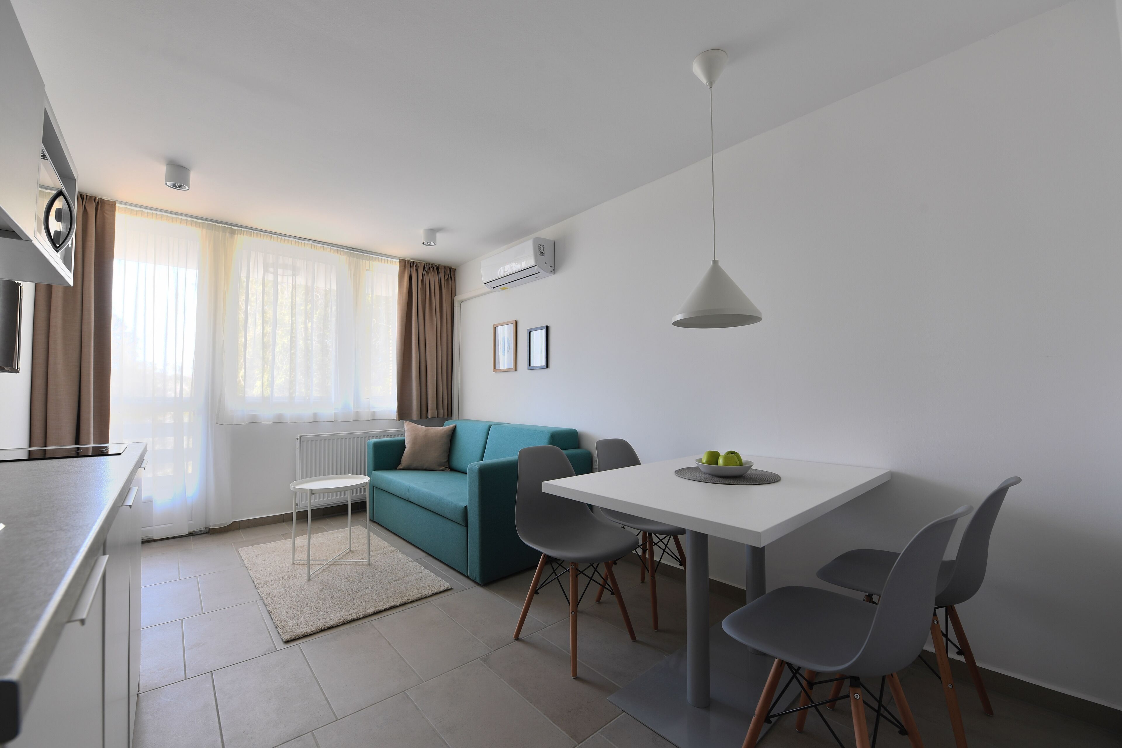 Un salon moderne comprenant un canapé, une table à manger, des chaises et un coin cuisine.