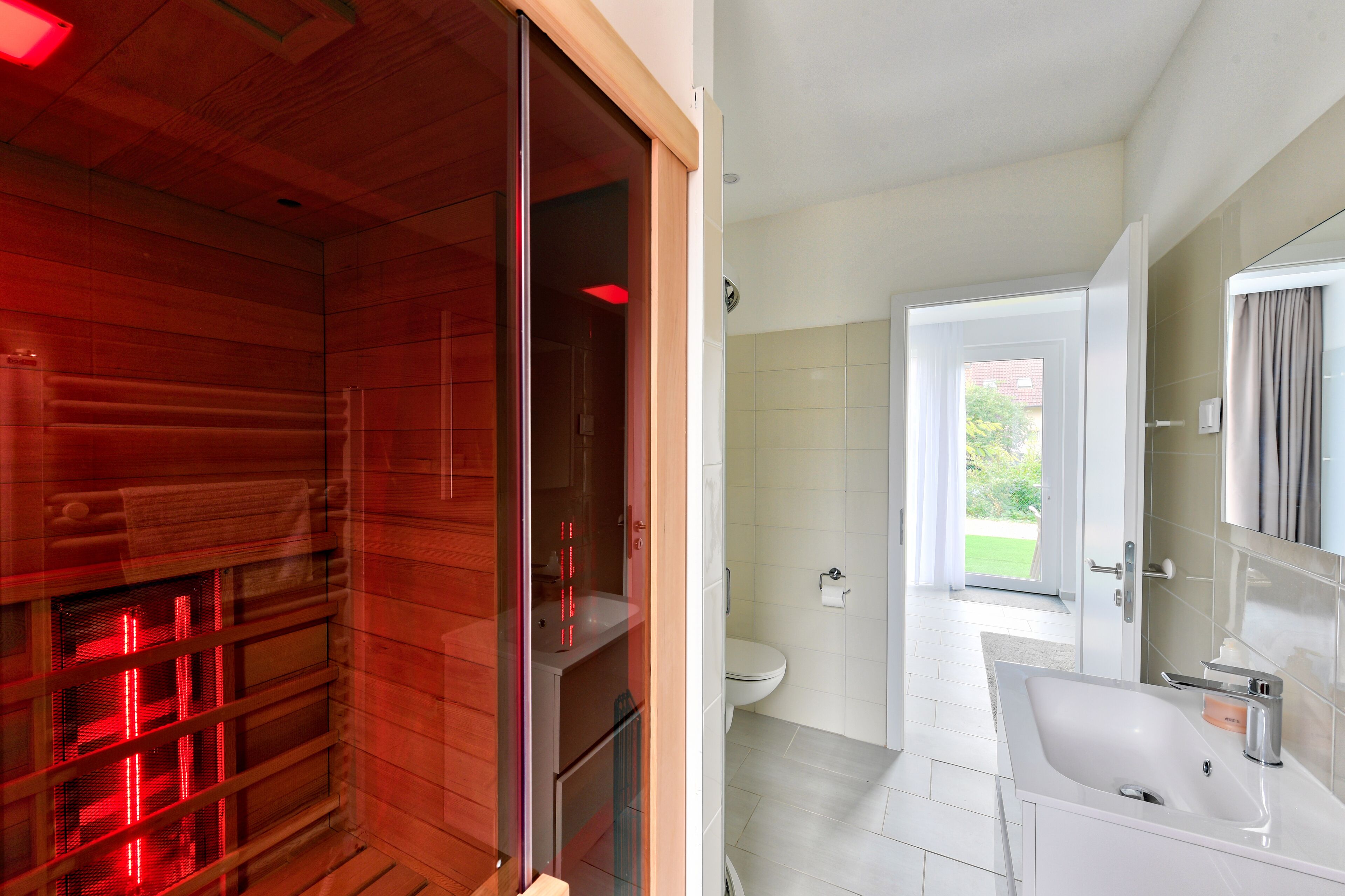 Een moderne badkamer met een glazen douchecabine, een wit wastafelmeubel en een grote spiegel.
