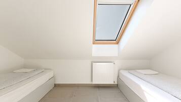 A small, clean room with two beds, a skylight, and a radiator.