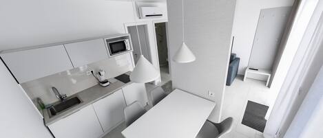 Una cocina moderna con armarios blancos, microondas integrado y comedor con mesa y sillas blancas.