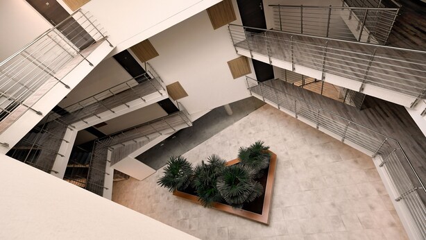 A multi-level atrium with a central planter with various plants, multiple staircases, and a modern architectural design. - Villa Oliver Hévíz 1 (Hévíz)