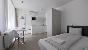 A modern hotel room with a bed, a desk, and a kitchenette. - Villa Oliver Hévíz 1 (Hévíz)