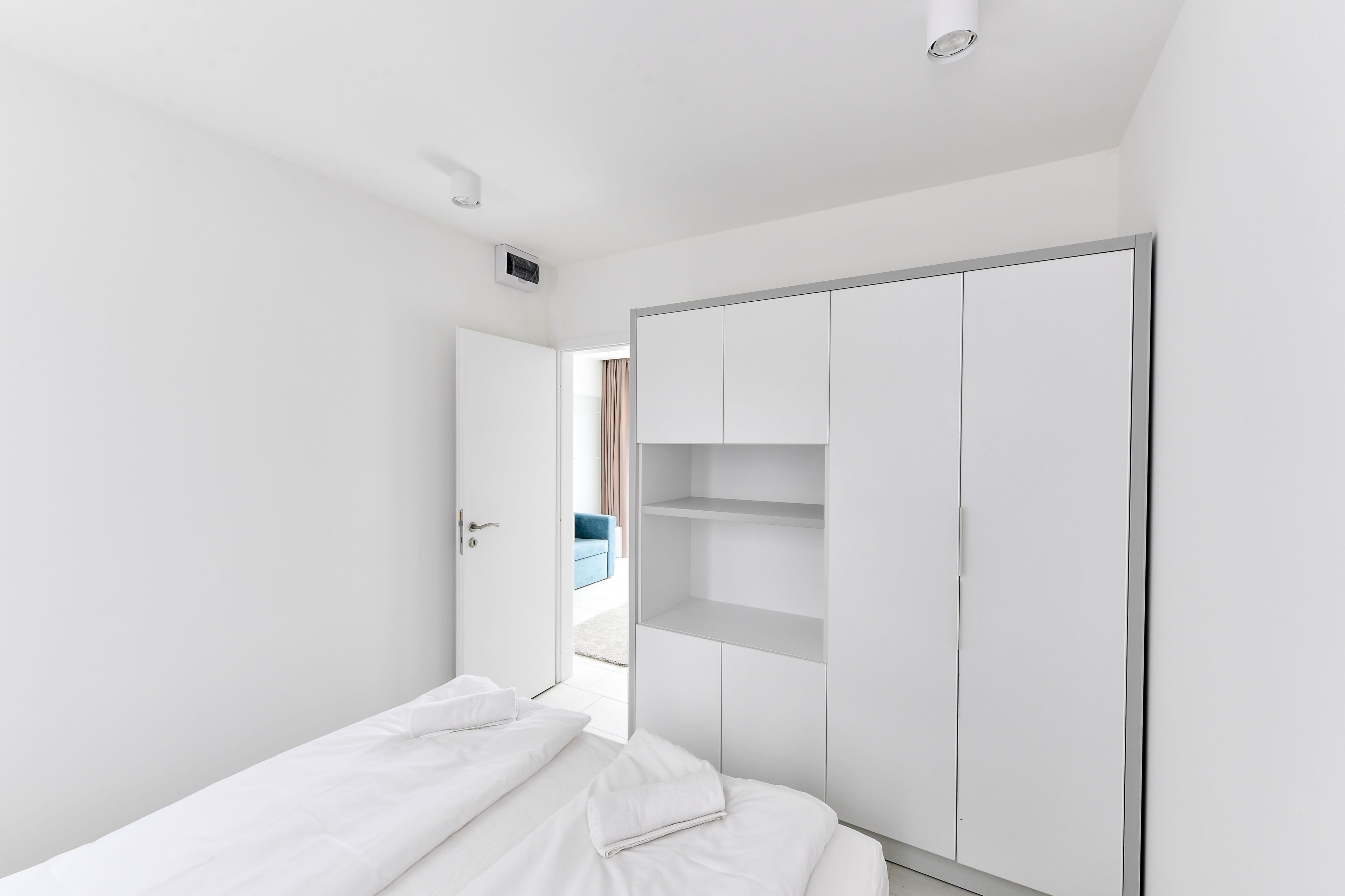 Un dormitorio minimalista con cama, armario y puerta que da a otra habitación.