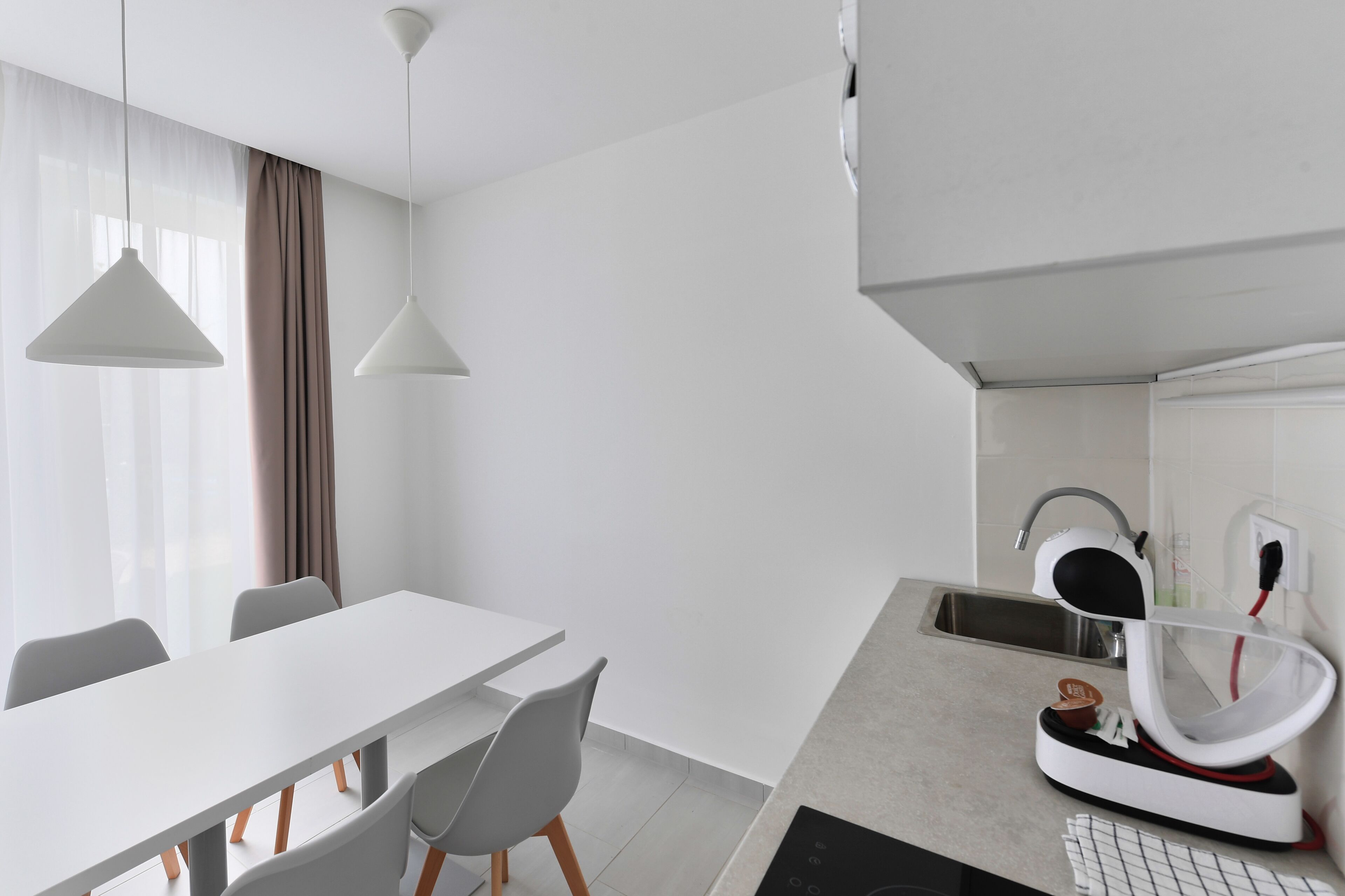A modern kitchen with a white countertop, a built-in oven, and a sink.