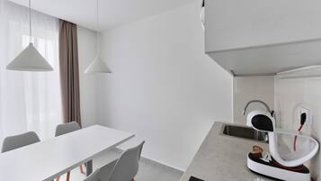 A modern kitchen with a white countertop, a built-in oven, and a sink.