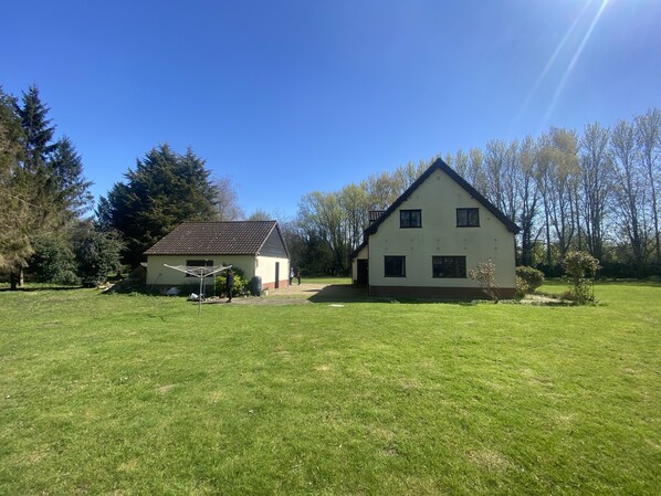 A two-story house with a sloped roof, a small attached garage, and a lawn in front. - Rivendell (Diss)