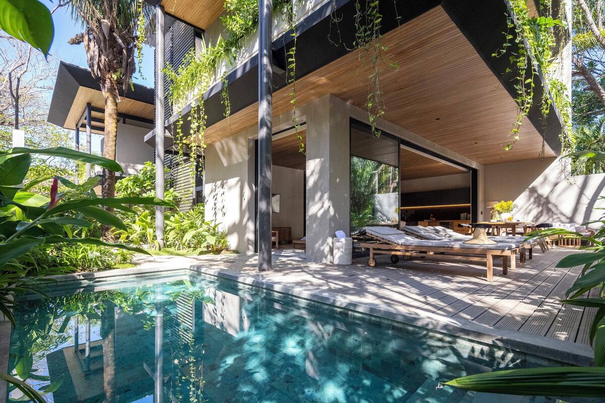 A modern outdoor pool area with lounge chairs and a wooden deck.