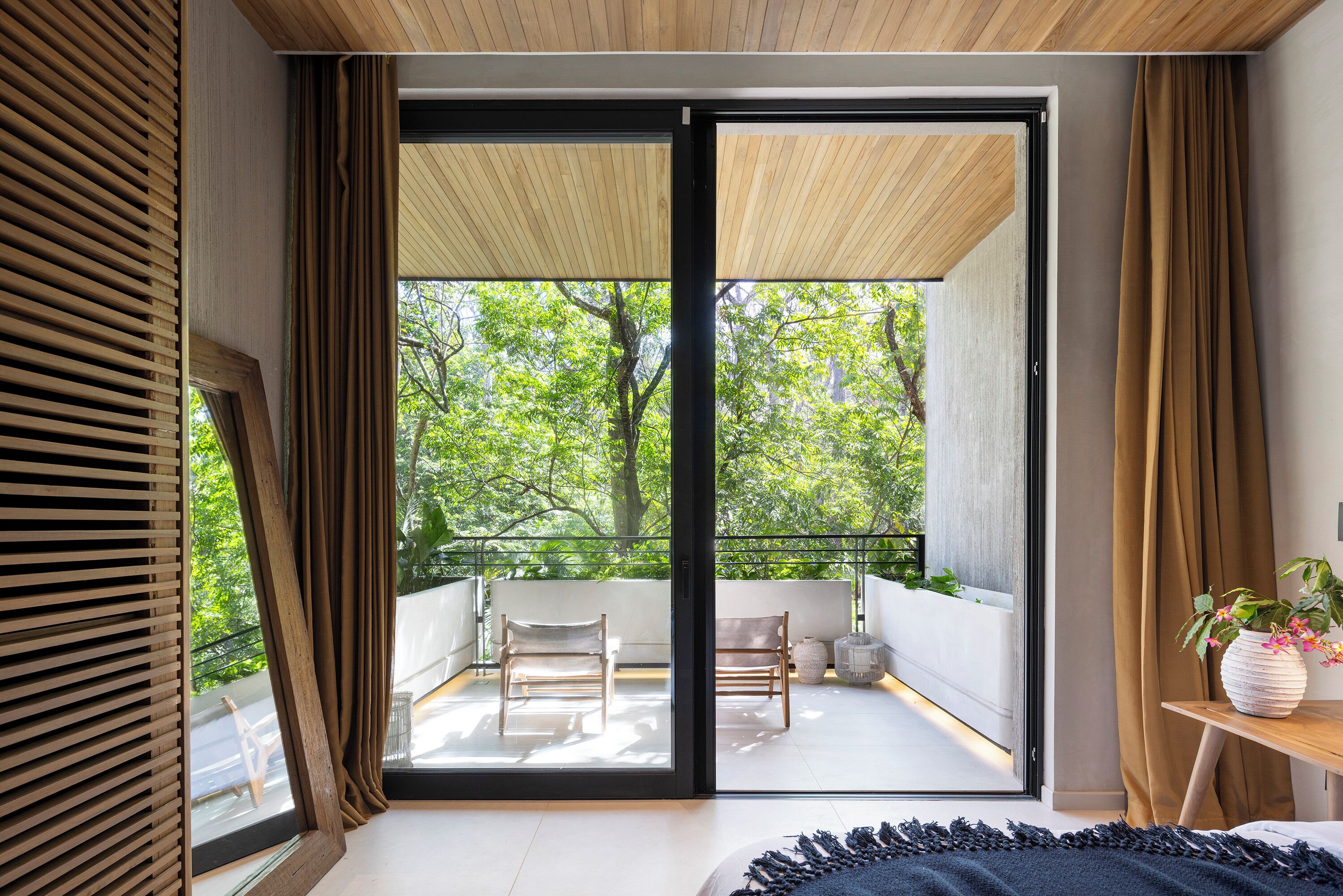 Ein modernes Schlafzimmer mit einem großen Schiebeglasfenster, das auf einen Balkon im Freien führt.