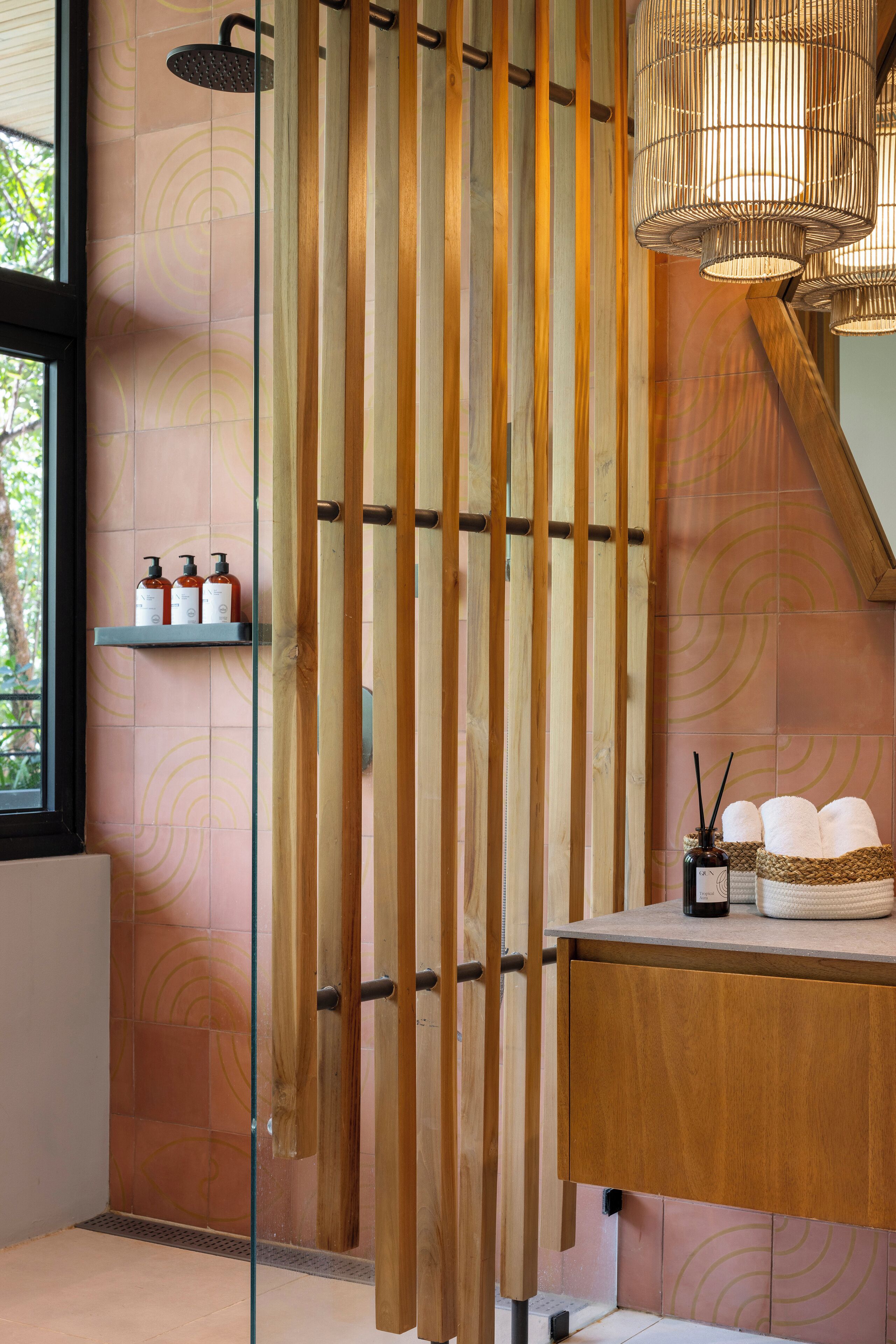 A bathroom with a shower, wooden slats, a shelf with toiletries, and a towel rack.