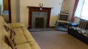 A living room with a fireplace, a television, and a sofa. - Come Along and Enjoy the Beautiful Moray Coast (Buckie)