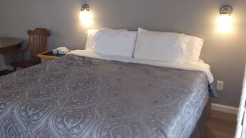 Ein Schlafzimmer mit einem Bett, zwei Wandleuchten, einem Holzstuhl und einem kleinen Tisch.