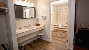 A bathroom with two sinks, a mirror, and a shower area. - Prairie Voyager  (Prairie Du Chien)
