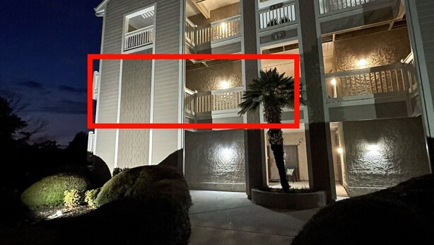 Een meerlaags woongebouw met balkons en een goed verlichte ingang.