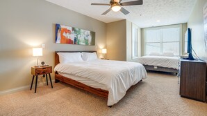 A bedroom with a bed, bedside table, lamp, ceiling fan, and artwork on the wall. - Downtown St Joseph Condo w/ Balcony & Harbor View (St Joseph)