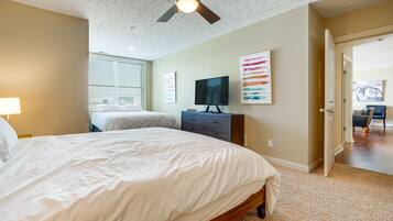 A bedroom with a large bed, a ceiling fan, a TV, and artwork on the wall.
