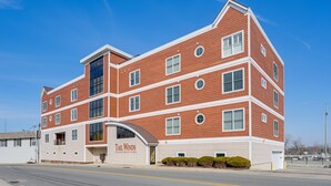 A multi-story building with a red brick facade, large windows, and a sign reading "Tail Winds Condominiums." - Downtown St Joseph Condo w/ Balcony & Harbor View (St Joseph)