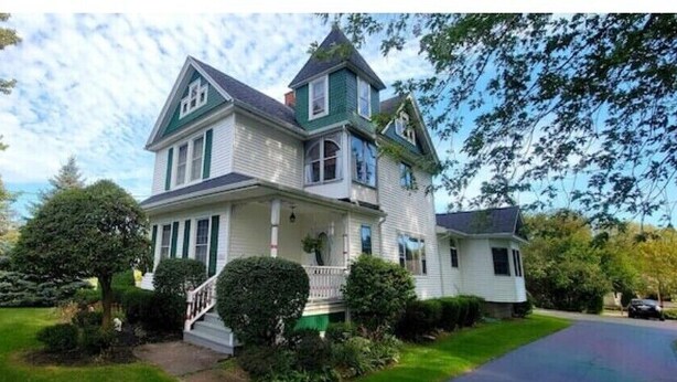 A two-story house with a wrap-around porch, a chimney, and a well-maintained lawn. - Victoria House luxurious country feel. Close to Buffalo Bills stadium. (Elma Center)