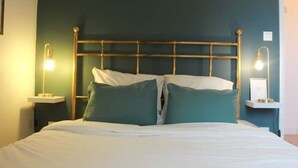 A bed with a gold headboard, two bedside lamps, and a white nightstand. - L'amiral Centre Ville Balnéo Parking (Grasse)