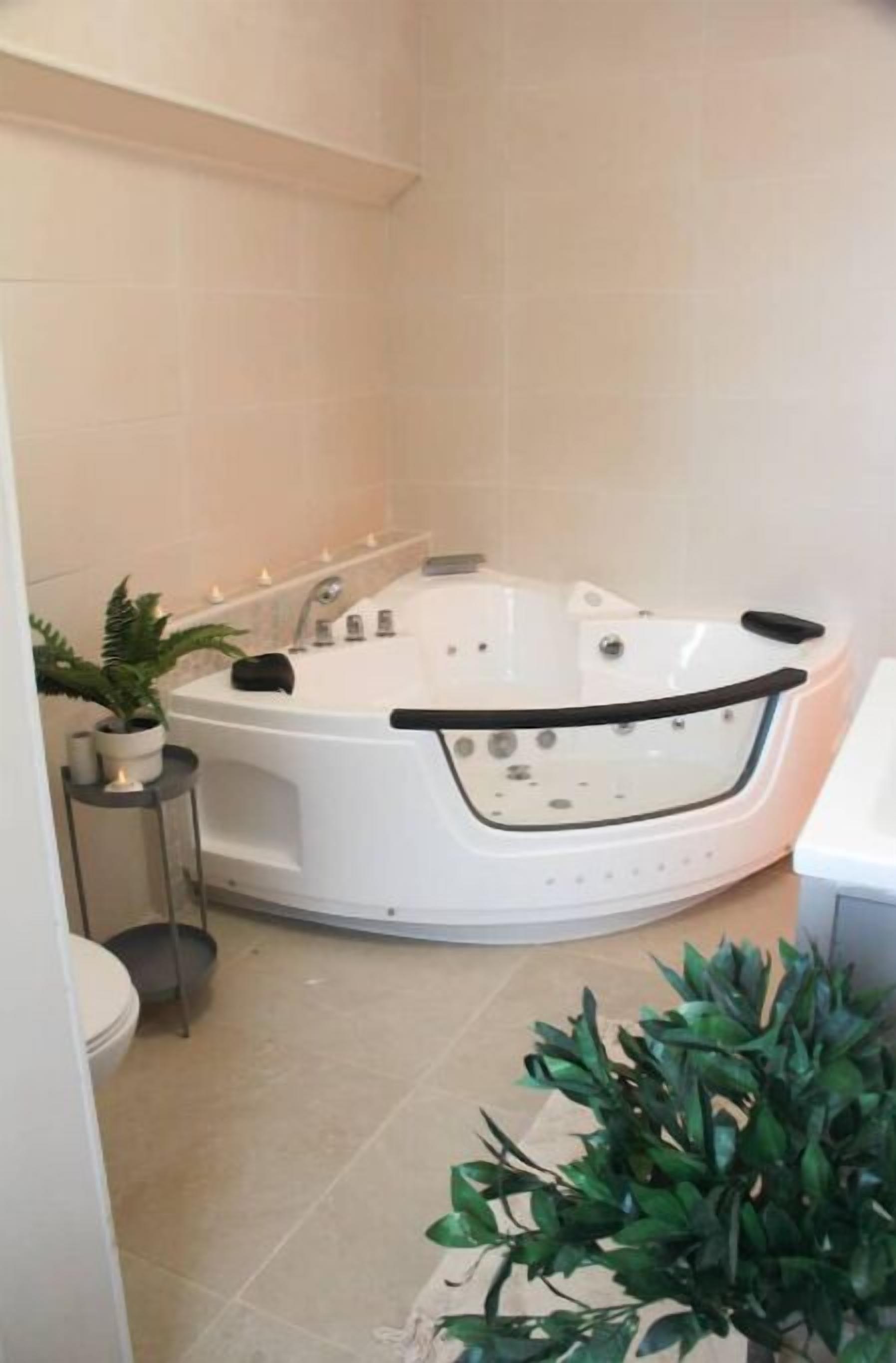 Et moderne badeværelse med et fristående badekar, en lille plantepotte og et toilet.