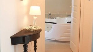 A hallway leading to a bathroom with a bathtub and a mirror on the wall. - L'amiral Centre Ville Balnéo Parking (Grasse)