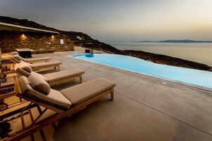 Una piscina al aire libre, sombrillas, sillones reclinables de piscina