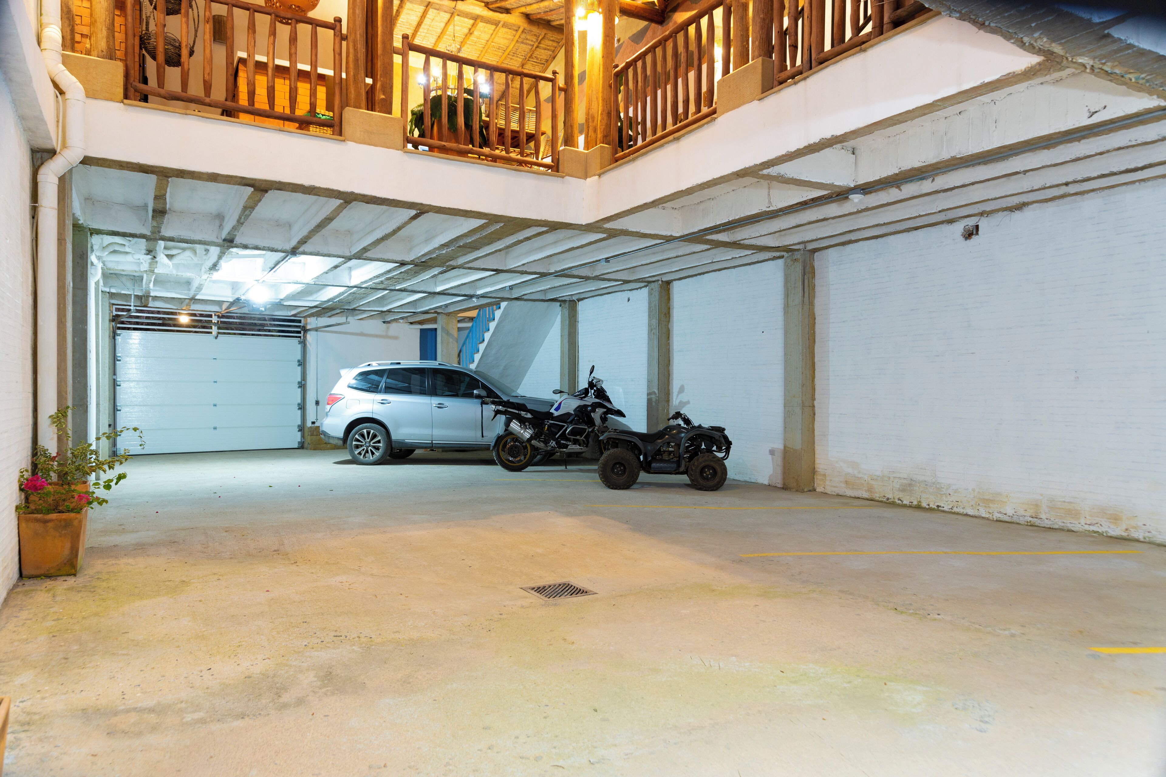 A multi-level parking garage with a white car and an ATV in the lower level.