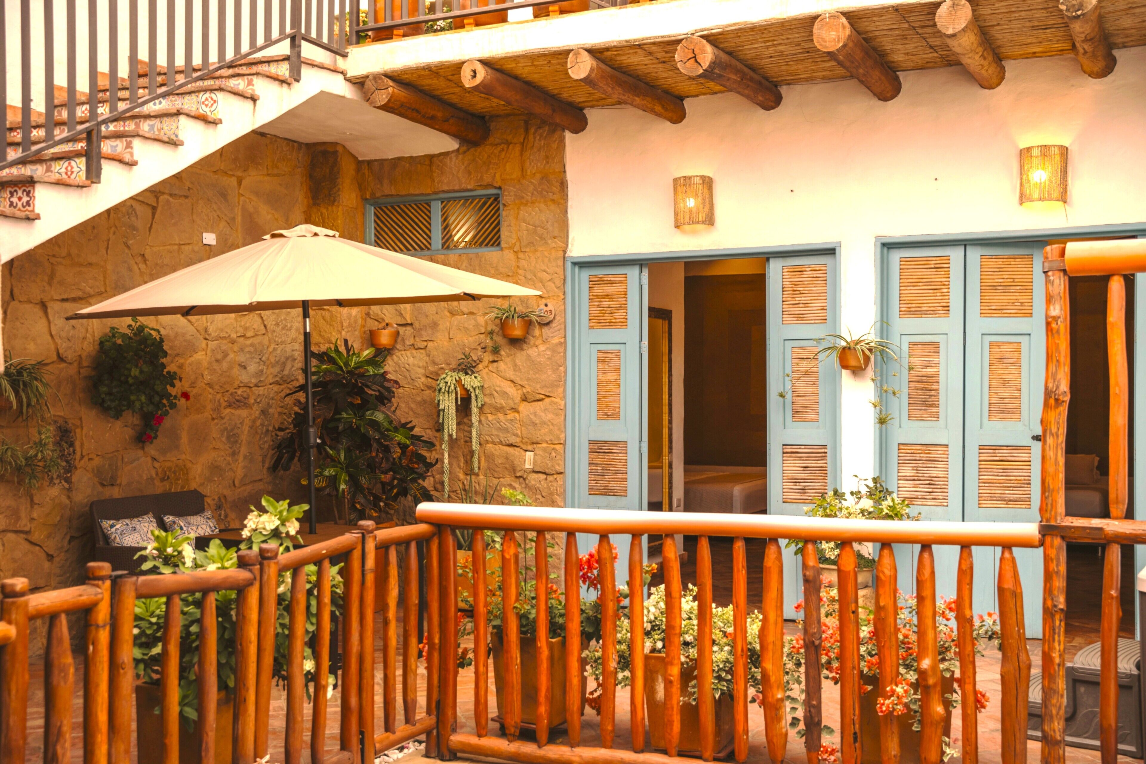 A stone building with wooden balconies, potted plants, and a staircase.